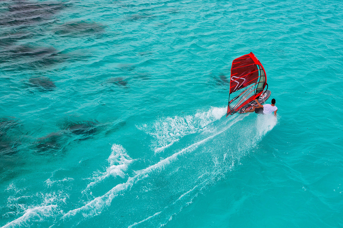 Aerial view of a man windsurfing on vibrant turquoise waters in Australia. Adventure and excitement captured in a stunning setting.